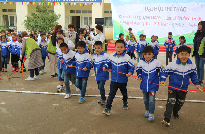 베트남 동로이 초등학교에서 베트남 초등학생 7명이 웃으며 리본컷팅식을 진행하고 있는 이미지